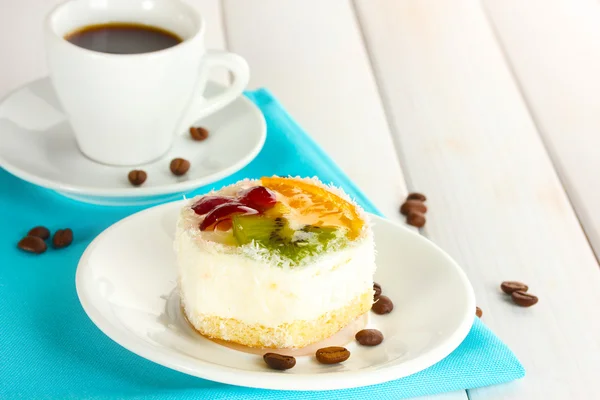 Чашка кофе и сладкие пирожные с фруктами на деревянном столе — стоковое фото