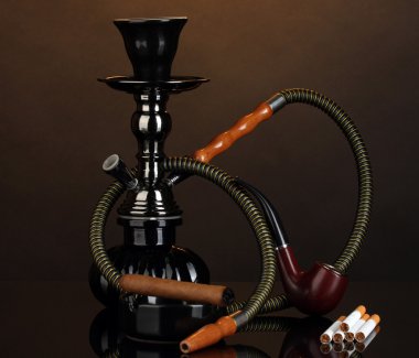 Smoking tools - a hookah, cigar, cigarette and pipe on brown background clipart