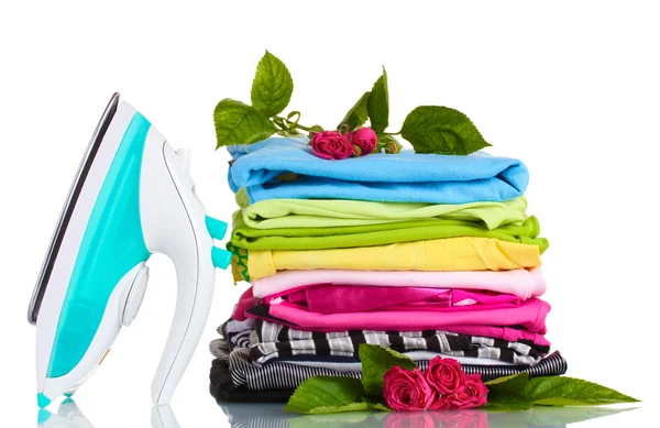 Σωρό από πολύχρωμα ρούχα και ηλεκτρικό σίδερο με τριαντάφυλλα που απομονώνονται σε λευκό — Φωτογραφία Αρχείου