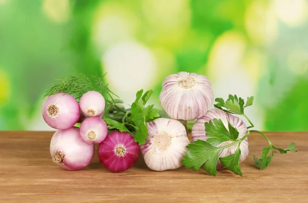 Young garlic and onion on wooden table on bright green background close-up — Stock Photo, Image