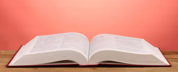 Öppna bok på träbord på röd bakgrund — Stockfoto
