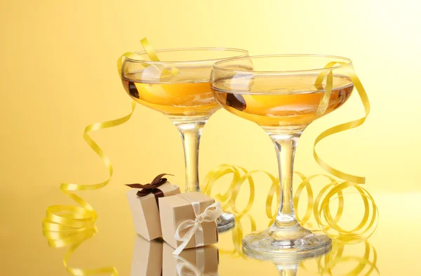 Bicchieri di champagne, regali e stelle filanti su sfondo giallo — Foto Stock
