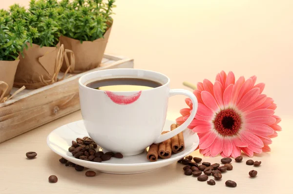 Чашка кави з помадою та бобами гербери, паличками кориці на дерев'яному столі — стокове фото