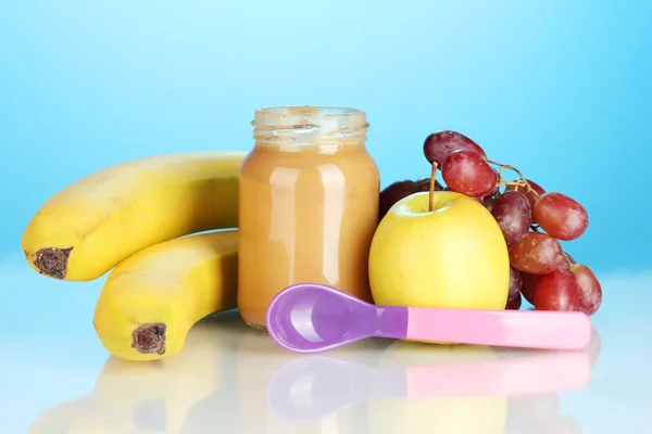 Jar with fruit baby food and spoon on colorful background — Stock Photo, Image