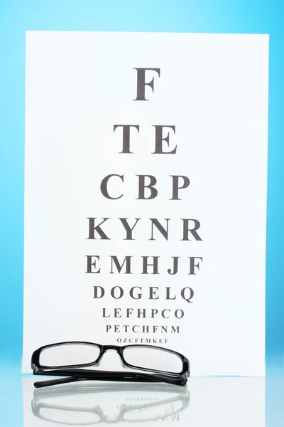 Gezichtsvermogen test-chart met bril op blauwe achtergrond close-up — Stockfoto