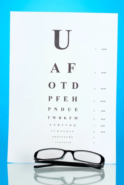 青色の背景はクローズ アップの眼鏡と視力テスト グラフ — ストック写真