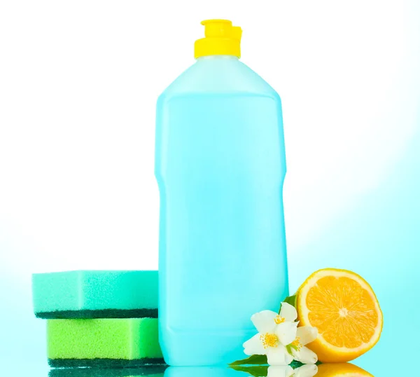 Mytí nádobí se houby a citronem s květinami na modrém pozadí — Stock fotografie