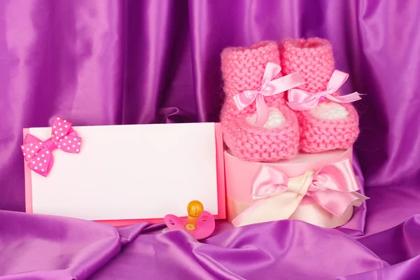 Botas de bebé de color rosa, pacifierd, postal y regalos sobre fondo de seda — Foto de Stock