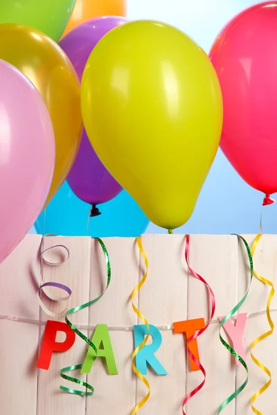 Partij. ballonnen tegen een houten hek op blauwe achtergrond — Stockfoto