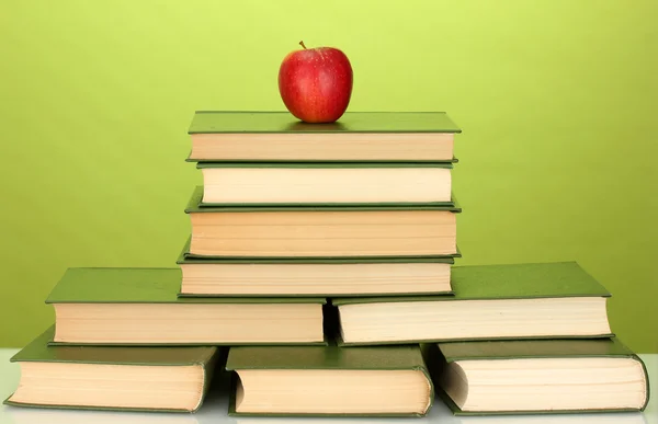 Pile of books with apple on green background close-up — Stock Photo, Image
