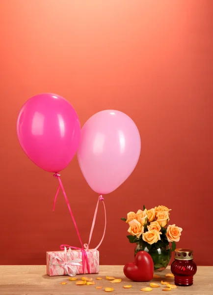 Romantyczny prezent dziewczyna. kolorowe balony gospodarstwa prezent na czerwonym tle — Zdjęcie stockowe