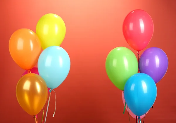 Kleurrijke ballonnen op rode achtergrond — Stockfoto