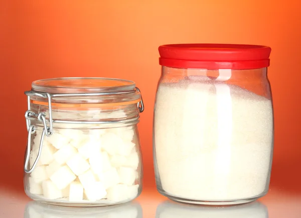 Tarro con azúcar cristalina blanca y azucarero con azúcar en terrón blanco sobre fondo colorido — Foto de Stock