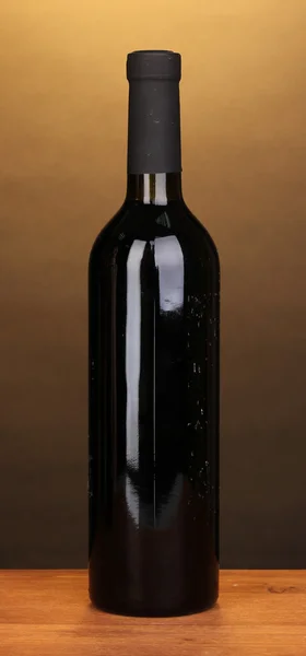 Butelka wina wielki na drewnianym stole na brązowym tle — Zdjęcie stockowe