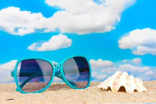Elegant women's sunglasses with shell at the beach — Stock Photo, Image
