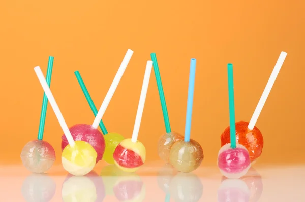 Lollipops brilhantes e deliciosos no fundo laranja close-up — Fotografia de Stock