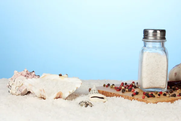 Sea salt on the beach and on the cutting board on a blue background — Stock Photo, Image