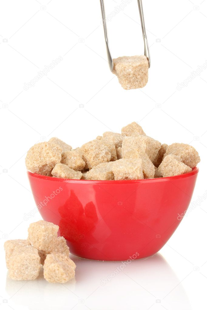 Brown cane sugar cubes in bowl with sugar-tongs on white background