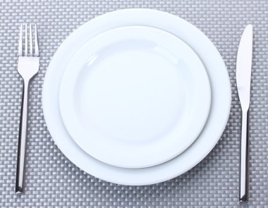 beyaz boş tabak çatal ve bıçak üzerinde gri bir masa örtüsü