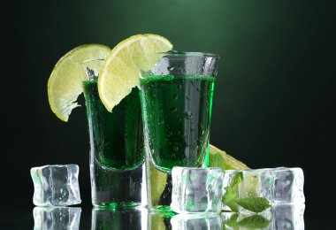 Two glasses of absinthe, lime and ice on green background clipart