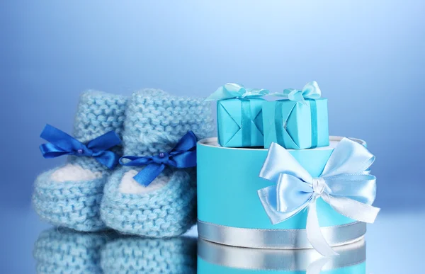 Güzel hediyeler ve bebek patik mavi zemin üzerine — Stok fotoğraf