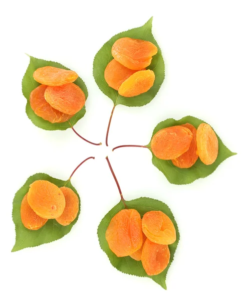Вкусные сушеные абрикосы на зеленых листьях, изолированных на белых — стоковое фото