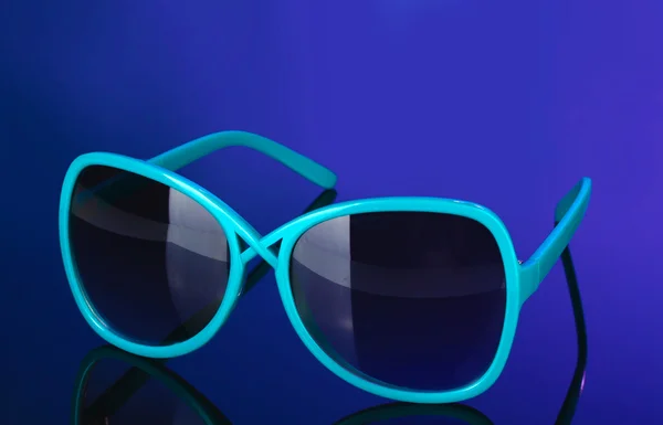 Óculos de sol azuis femininos na moda em fundo colorido brilhante — Fotografia de Stock