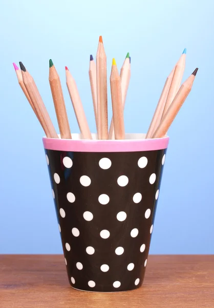 Kleur potloden in glas op houten tafel op blauwe achtergrond — Stockfoto