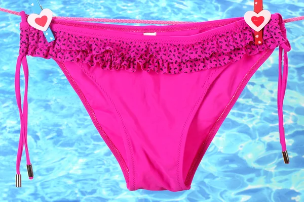 Damskie spodnie strój kąpielowy wiszące na liny na tle wody — Zdjęcie stockowe
