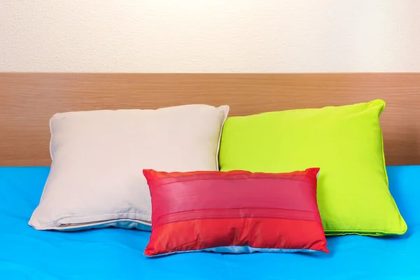 Bright pillows on bed on beige background — Stock Photo, Image