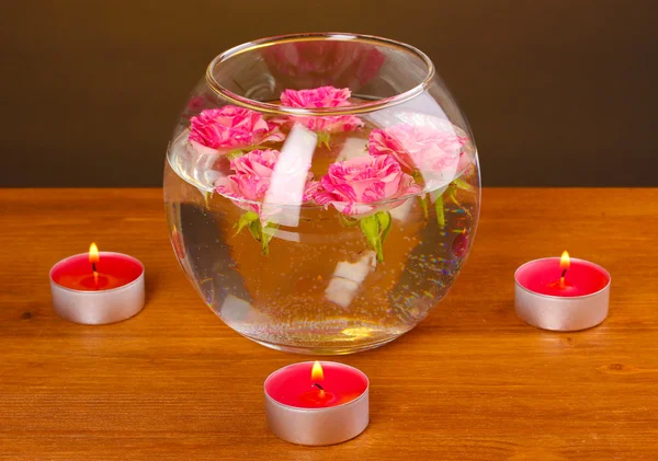 Спа композиция свечей и розовых роз, плавающих на деревянном фоне — стоковое фото
