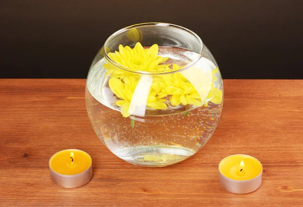 Složení lázně světle svíček a žlutá chryzantéma plovoucí na dřevěné pozadí — Stock fotografie