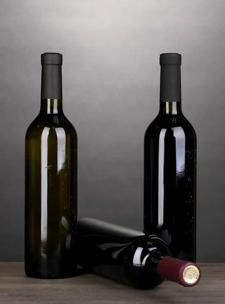 Lahví značkového vína na dřevěný stůl na šedém pozadí — Stock fotografie
