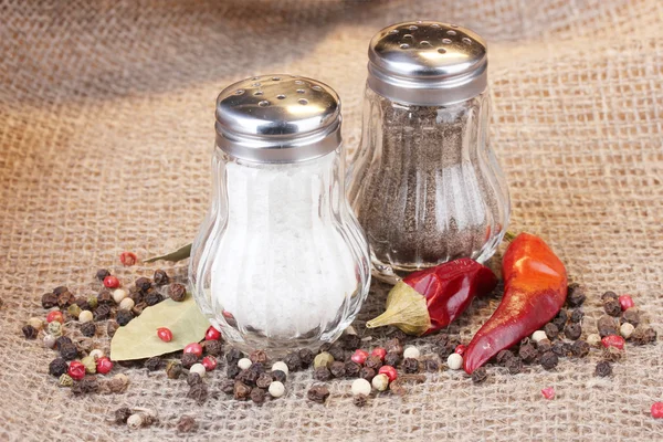 Molinos de sal y pimienta y especias sobre fondo de arpillera — Foto de Stock
