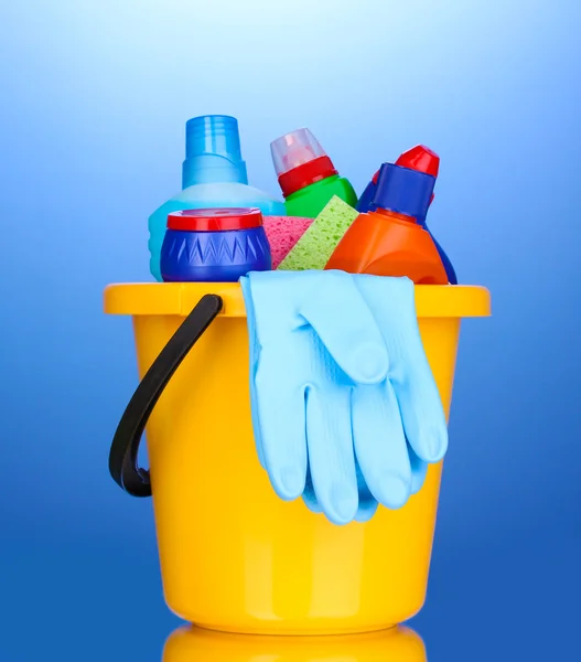 Secchio con oggetti per la pulizia su sfondo blu — Foto Stock