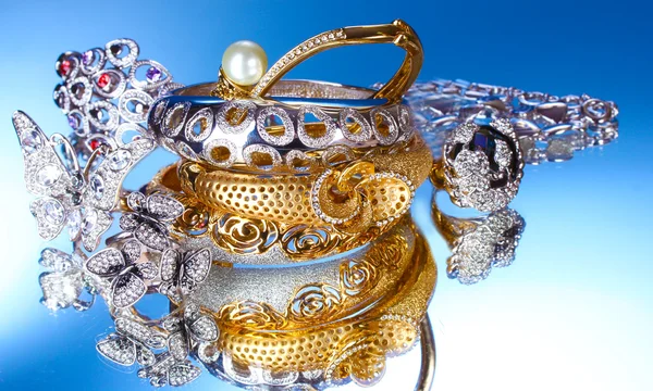 Bellissimi bracciali e anelli in argento e oro su sfondo blu — Foto Stock