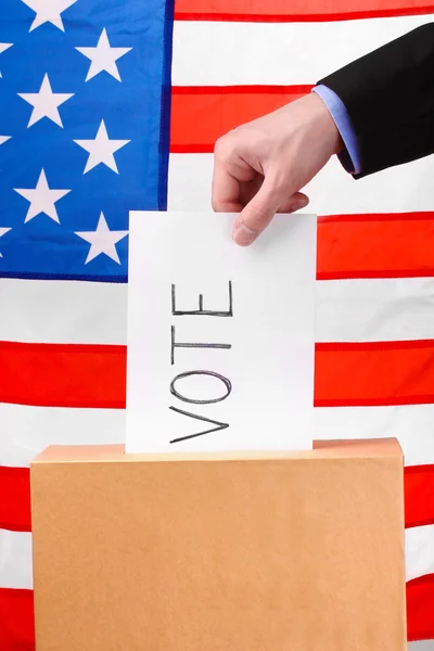 Рука з виборчих бюлетенів і коробка на Прапор США — стокове фото