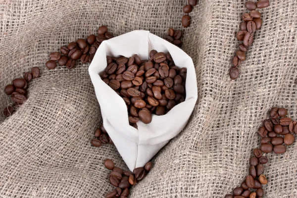 Coffee beans in sack on canvas background — Stock Photo, Image