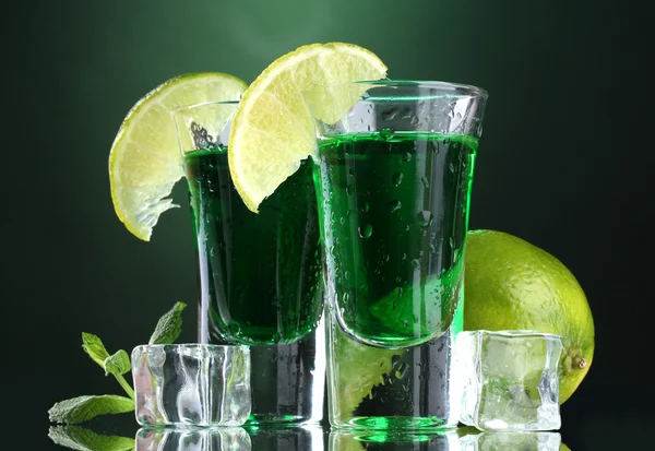 Twee glazen van Absint, kalk en ijs op groene achtergrond — Stockfoto