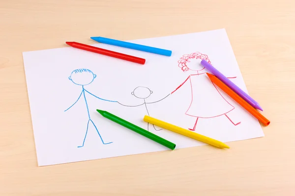 Children's drawing of family and pencils on wooden background — Stock Photo, Image