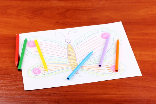 Детский рисунок бабочки и карандашей на деревянном фоне — стоковое фото