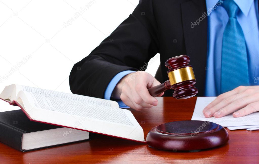 Wooden gavel in hand and books on wooden table on gray background