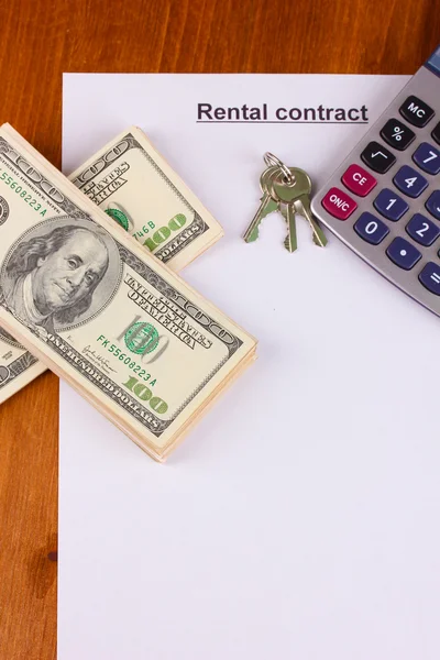 Rental contract with dollars on wooden background close-up