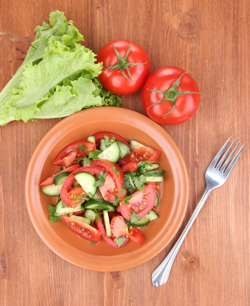 Salade fraîche avec tomates et concombres sur fond de bois — Photo