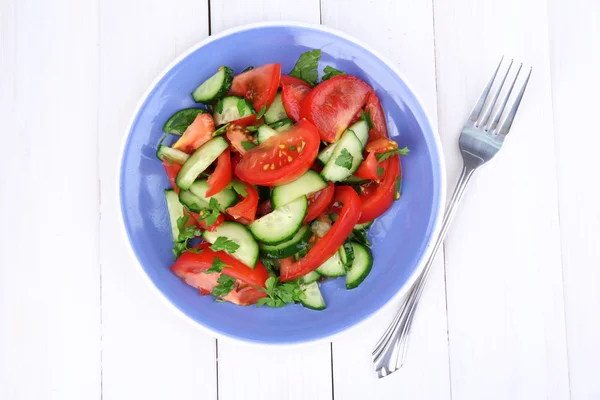 Salade fraîche avec tomates et concombres sur fond de bois blanc — Photo