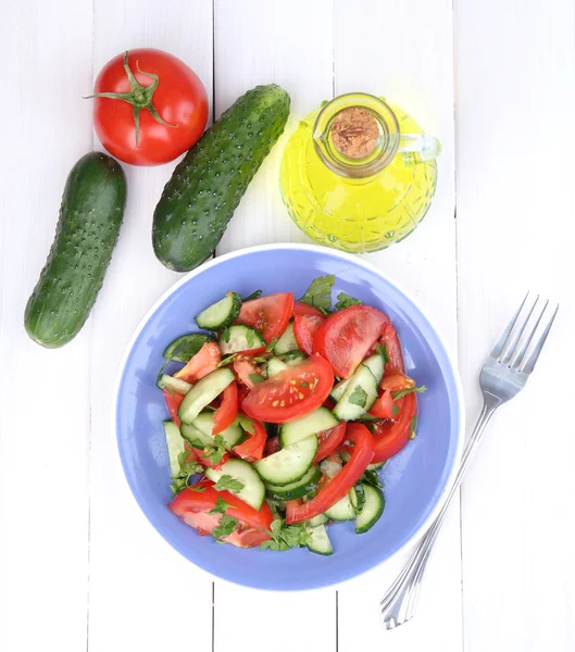 Salade fraîche avec tomates et concombres sur fond de bois blanc — Photo