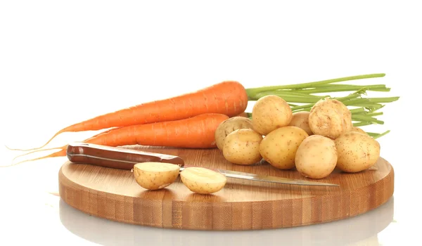 Papas jóvenes y zanahorias en una tabla de cortar con cuchillo aislado en blanco —  Fotos de Stock