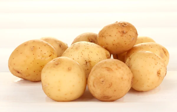 Batatas jovens em mesa de madeira branca close-up — Fotografia de Stock