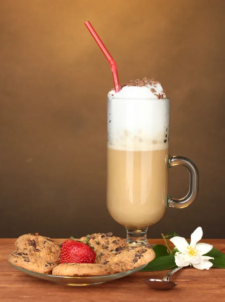 Verre de café cocktail avec biscuits et fraise sur soucoupe et fleur sur fond brun — Photo