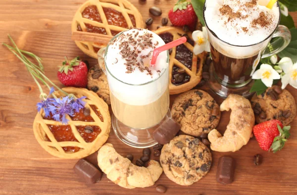 Vasos de café cóctel sobre mesa de madera con dulces y flores —  Fotos de Stock